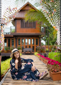 Portrait of young woman sitting on potted plant