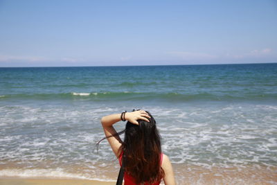 Young woman at beach against sky