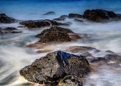 Scenic view of sea waves against rocks