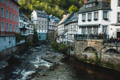 Arch bridge over river amidst buildings in city