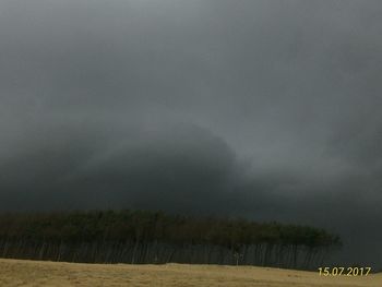 Scenic view of field against storm clouds