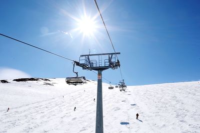 Ski lift on snowcapped mountains against blue sky