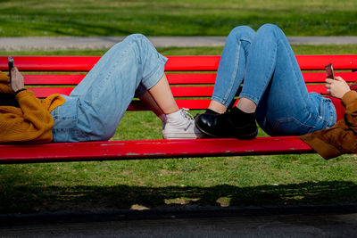 Low section of men sitting on bench in park