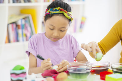 Girl painting easter egg at home