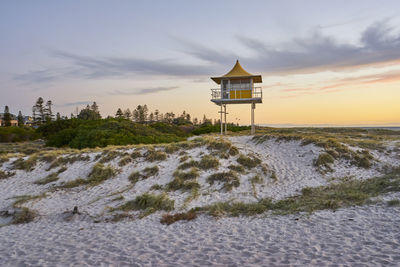 Lifeguard hut on beach against sky during sunset