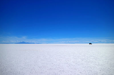 Scenic view of snow covered land against blue sky