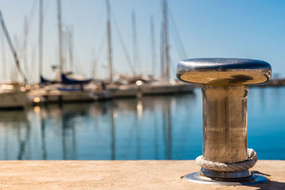 Close-up of sailboats moored at harbor against clear blue sky