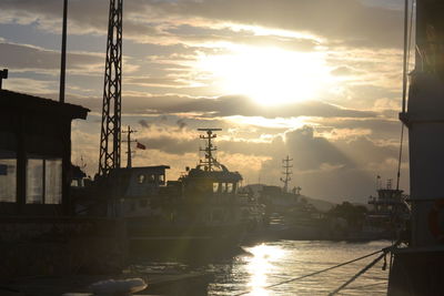 Sailboats moored at harbor against sky during sunset