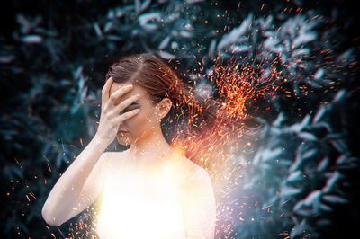 Close-up of woman standing against sparks
