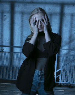 Portrait of young woman standing against wall