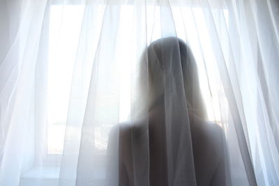 Close-up of woman against white curtain
