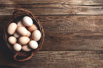 Flat lay with basket full of organic chicken eggs on wooden background. organic household concept
