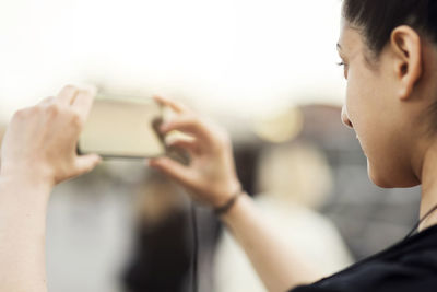 Cropped image of woman photographing from mobile phone