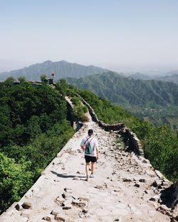 Rear view of woman walking on mountain against clear sky