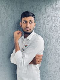 Portrait of young man standing against wall