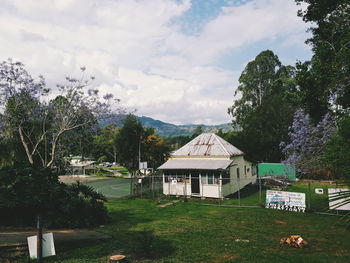 Houses and trees on field against sky