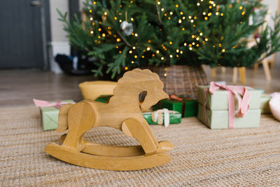 Wooden horse toy wheelchair on the background of christmas tree lights and gifts with copy space