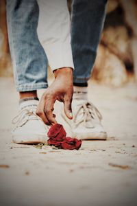 Low section of man picking rose on road