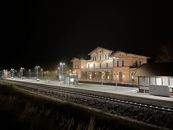 Railroad tracks by buildings against clear sky at night