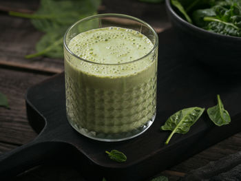 Glass of homemade healthy green smoothie with fresh baby spinach