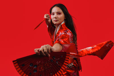 Young woman holding gift box against yellow background