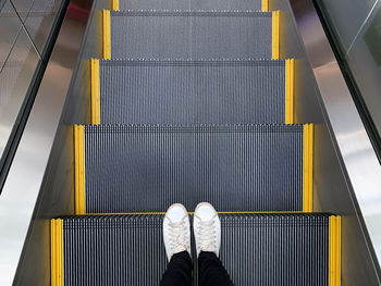 Low section of person standing on escalator