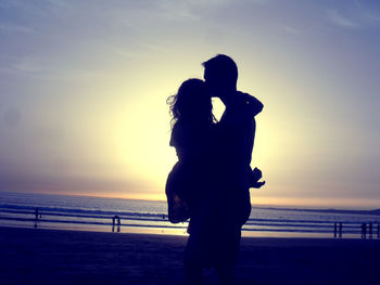 Silhouette couple on beach during sunset