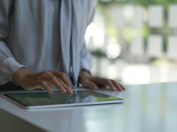 Midsection of businesswoman using digital tablet on table