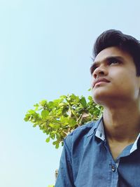 Portrait of young man looking away against sky