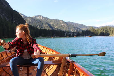 Woman sitting on boat in mountains against sky
