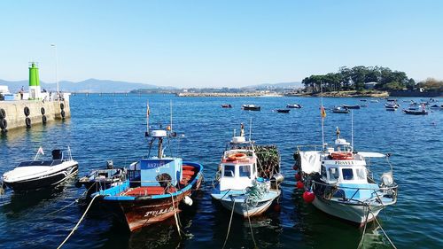 Boats moored in sea against clear sky