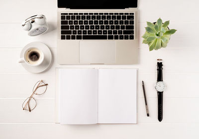 Overhead workspace with laptop, blank book for mockup and coffee