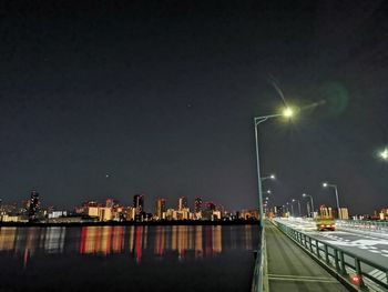 Illuminated bridge over city against sky at night