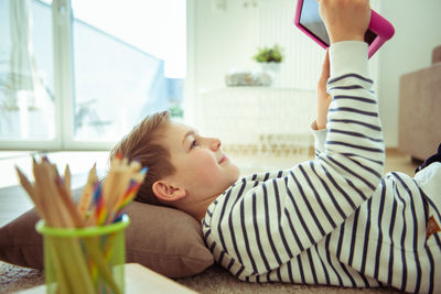 Boy using digital tablet while lying at home