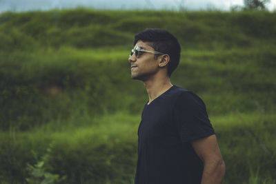 Young man looking away while standing on land