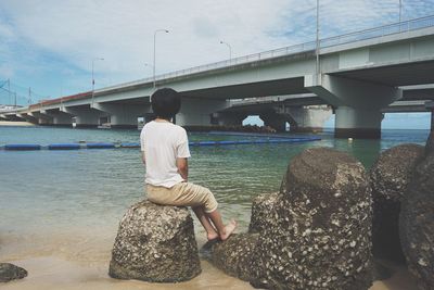 Rear view of man standing on bridge over river