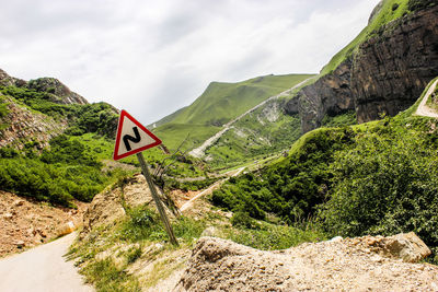 Scenic view of road by mountains against sky