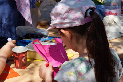 Close-up of girl cutting paper in sunny day