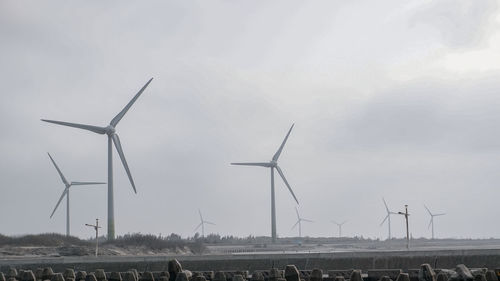 Windmills on field against sky