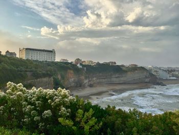 Scenic view of sea by buildings against sky