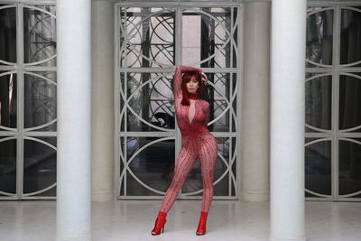 Portrait of young woman standing against wall