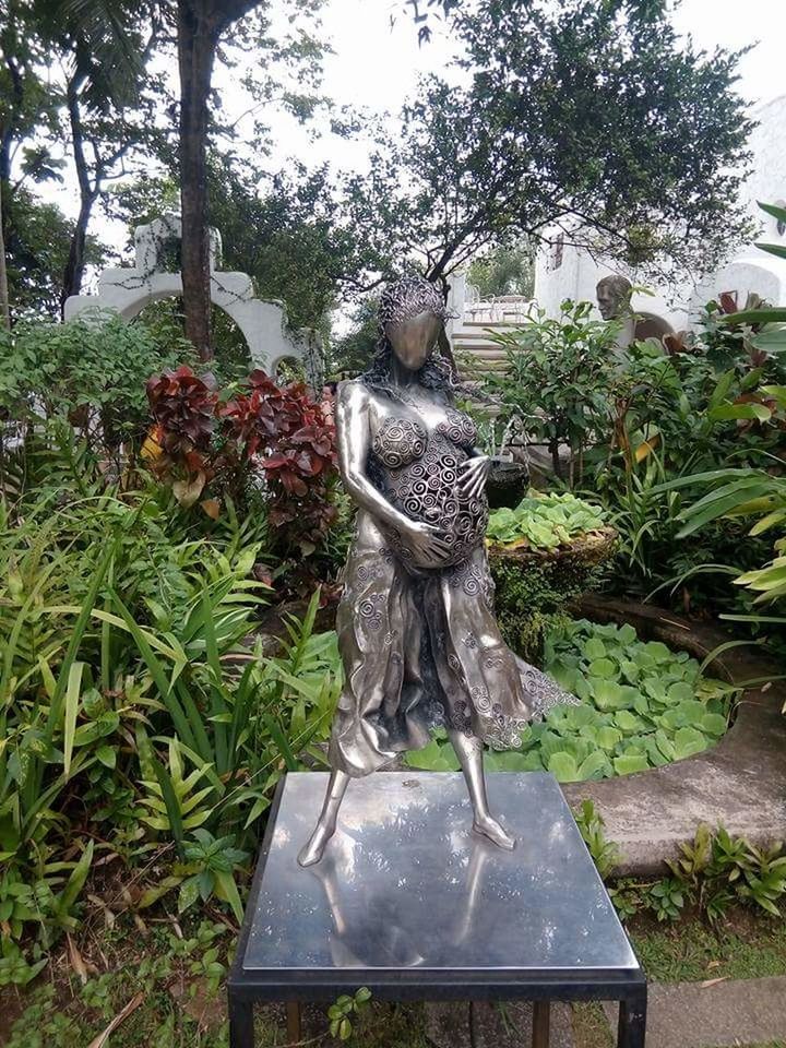 STATUE AMIDST TREES AGAINST SKY