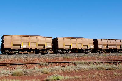 Freight train on railroad track against clear blue sky