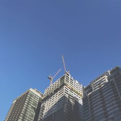 Low angle view of skyscrapers against clear blue sky
