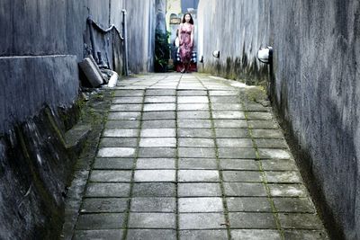 Woman walking on footpath amidst wall