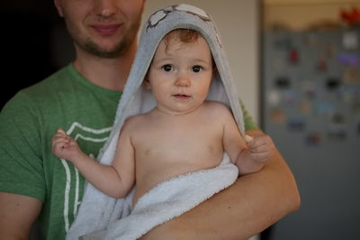 Baby girl in towel after bath held by her father