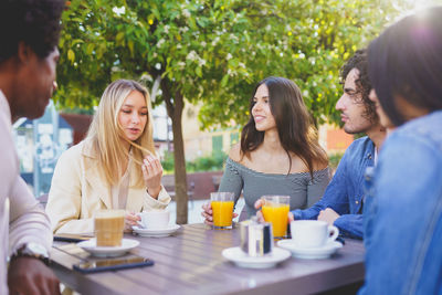 Smiling friends sitting on table