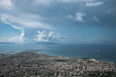 Aerial view of townscape by sea against sky