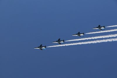 Low angle view of airshow against clear blue sky