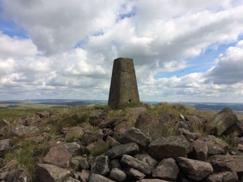 Lighthouse on landscape against cloudy sky